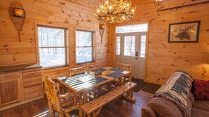 A wooden cabin interior with a dining table, benches, a chandelier, and a couch. - Beautiful ADK Getaway! Trail 4 and Lake Access!  Weekly Discount Available (Old Forge)