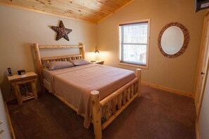 A cozy bedroom with a wooden bed, a star decoration, a bedside lamp, a window with blinds, and a circular mirror on the wall.