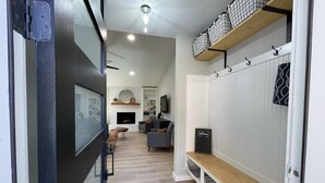 A modern living room with a fireplace, a sofa, and a TV. There is a wooden shelf with baskets and a welcome sign. - Great location! All New Super Private Modern Freshly Remodeled Retreat! (Cedar Park)