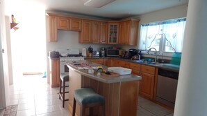 Una cucina con mobili in legno, un'isola centrale con sgabelli, un forno a microonde, un tostapane e un lavello.