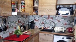 A compact kitchen with wooden cabinets, a microwave, a washing machine, and a small sink.