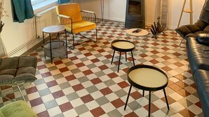 A living room with a checkered floor, a television, a sofa, a chair, a lamp, and a fireplace. - Wimereux: Large house ideally located 🏖, Les Arômes (Wimereux)