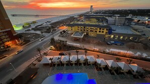 A hotel with a swimming pool, a pier extending into the sea, and a view of the ocean at sunset. - FALL DEALS! CALYPSO 3-1004 FREE BEACHSETUPS! Romantic Ocean View from KING Bed! (Panama City Beach)