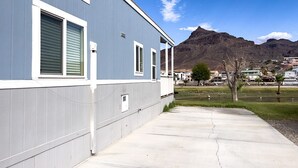 Un edificio moderno con un camino de hormigón y una montaña al fondo.