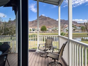 A covered outdoor area with two chairs and a table, overlooking a body of water and a mountainous landscape. - Siren's Adventure Riverfront Cottage! River Lodge NB31 (Parker Dam)