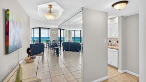 Un interior moderno con comedor, cocina y grandes ventanales con vistas al mar.