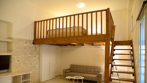 A room with a bunk bed, a sofa, a small table, and a TV. - Uni Island City Suites (Heraklion)