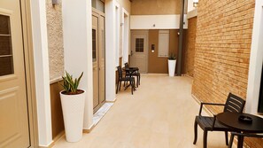 A narrow corridor with a potted plant, a table with chairs, and a door marked with the number 3. - Uni Island City Suites (Heraklion)