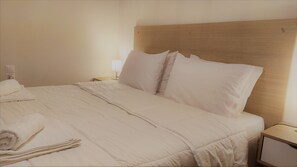 Restful retreat with a neatly made bed, nightstand, and lamp.