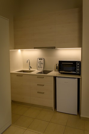 Compact kitchen with microwave oven, refrigerator, and sink, featuring a well-organized layout.