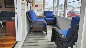 A covered porch with wicker chairs, a ceiling fan, and a view of the neighborhood.