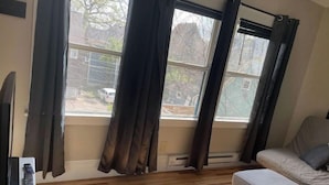 A room with a large window, a sofa, and a TV.