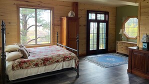 A wooden cabin bedroom with a bed, a dresser, a window, and a door. - Majestic Mountain Escape (Placerville)