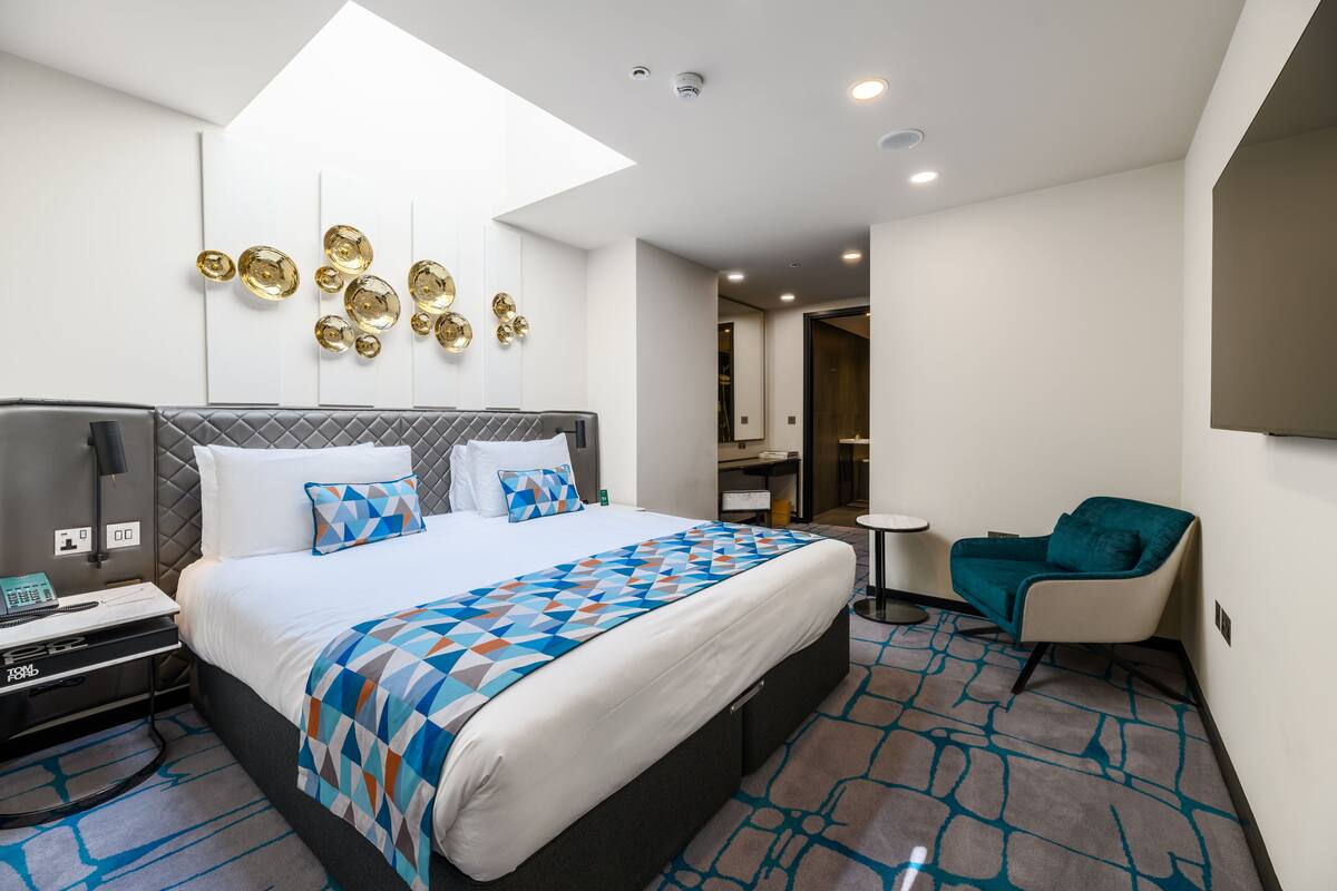 Une chambre d’hôtel moderne avec un grand lit, un bureau équipé d’un ordinateur, une chaise et une petite table.