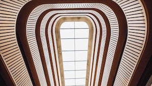 A modern hotel lobby with a central skylight, multiple levels, and seating areas.