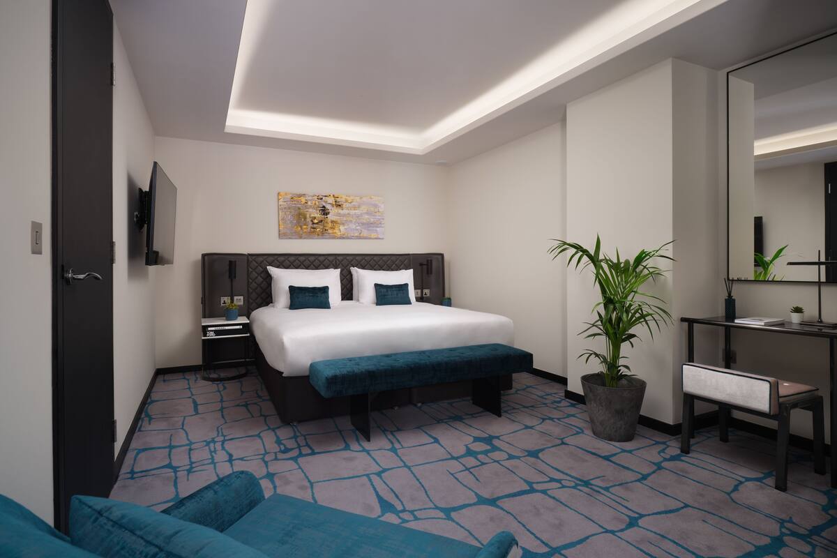 Une chambre d’hôtel moderne, dotée d’un grand lit, d’un bureau, d’une chaise, d’une plante en pot et d’un téléviseur à écran plat.