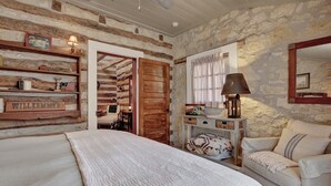 Una habitación acogedora con una cama, un sofá, una puerta de madera y una pared de piedra.