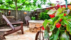 Un patio con piso de piedra, una silla de madera y una mesa con chimenea.