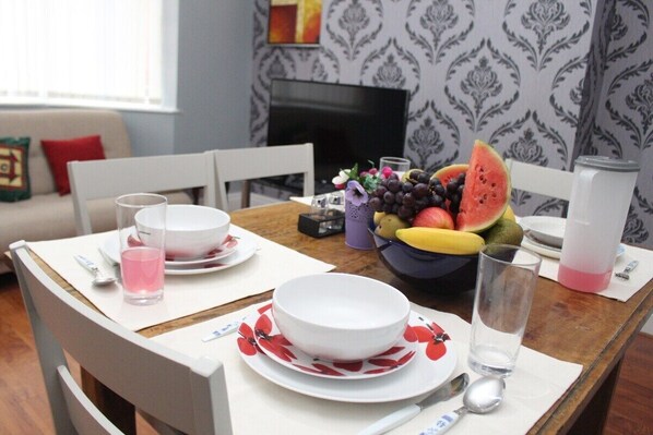 A dining table set with plates, bowls, and a fruit bowl.