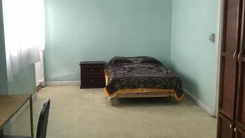 Quarto com cama, escrivaninha e guarda-roupa.