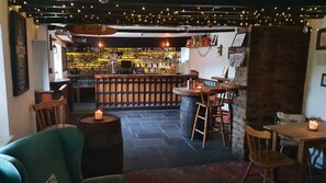Un coin bar accueillant, avec des meubles en bois, un mur en pierre et des guirlandes lumineuses.