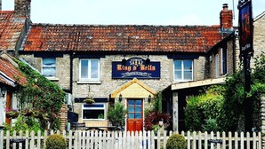 Un pub traditionnel appelé « Ring O’ Bells », avec une façade en pierre, une porte rouge et une enseigne.