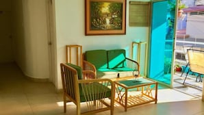 A room with a green sofa, wooden chairs, a small table, and a painting on the wall. - Hostal Casa Latina (Manta)