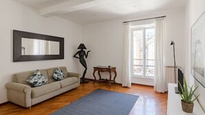 Una sala de estar con un sofá, una lámpara de pie, una mesita y una ventana con cortinas.