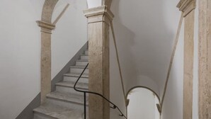 Una escalera con barandales de piedra y pasamanos, que conduce a un nivel superior.