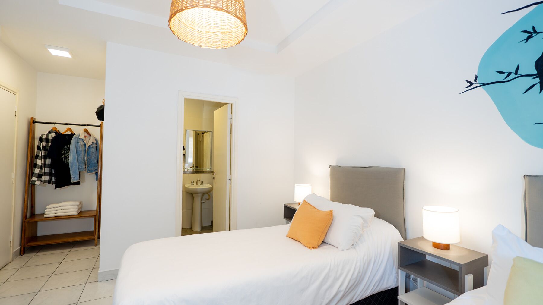 A hotel room with a bed, bedside tables, a wardrobe, and a bathroom visible through an open door.