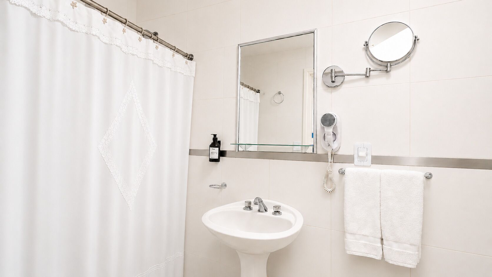 Une salle de bain avec un lavabo blanc, un miroir, un porte-serviettes et un rideau de douche.