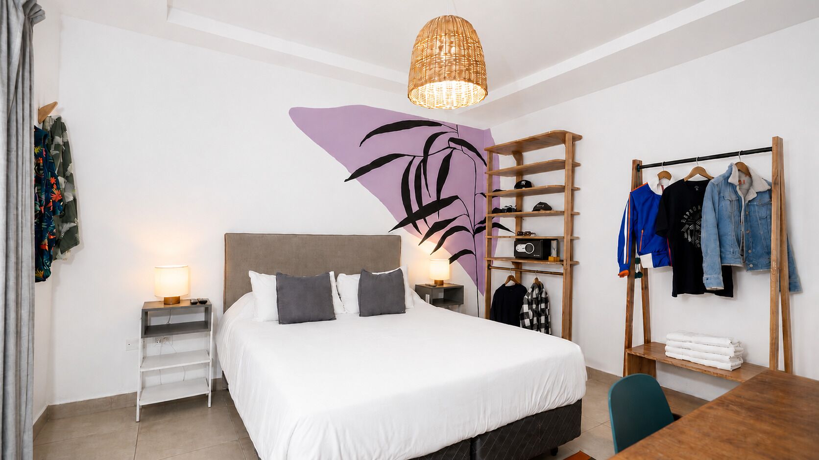 A hotel room with a bed, a bedside table with a lamp, a wardrobe, and a clothing rack.