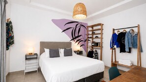 A hotel room with a bed, a bedside table with a lamp, a wardrobe, and a clothing rack. - Selina Salta (Salta)