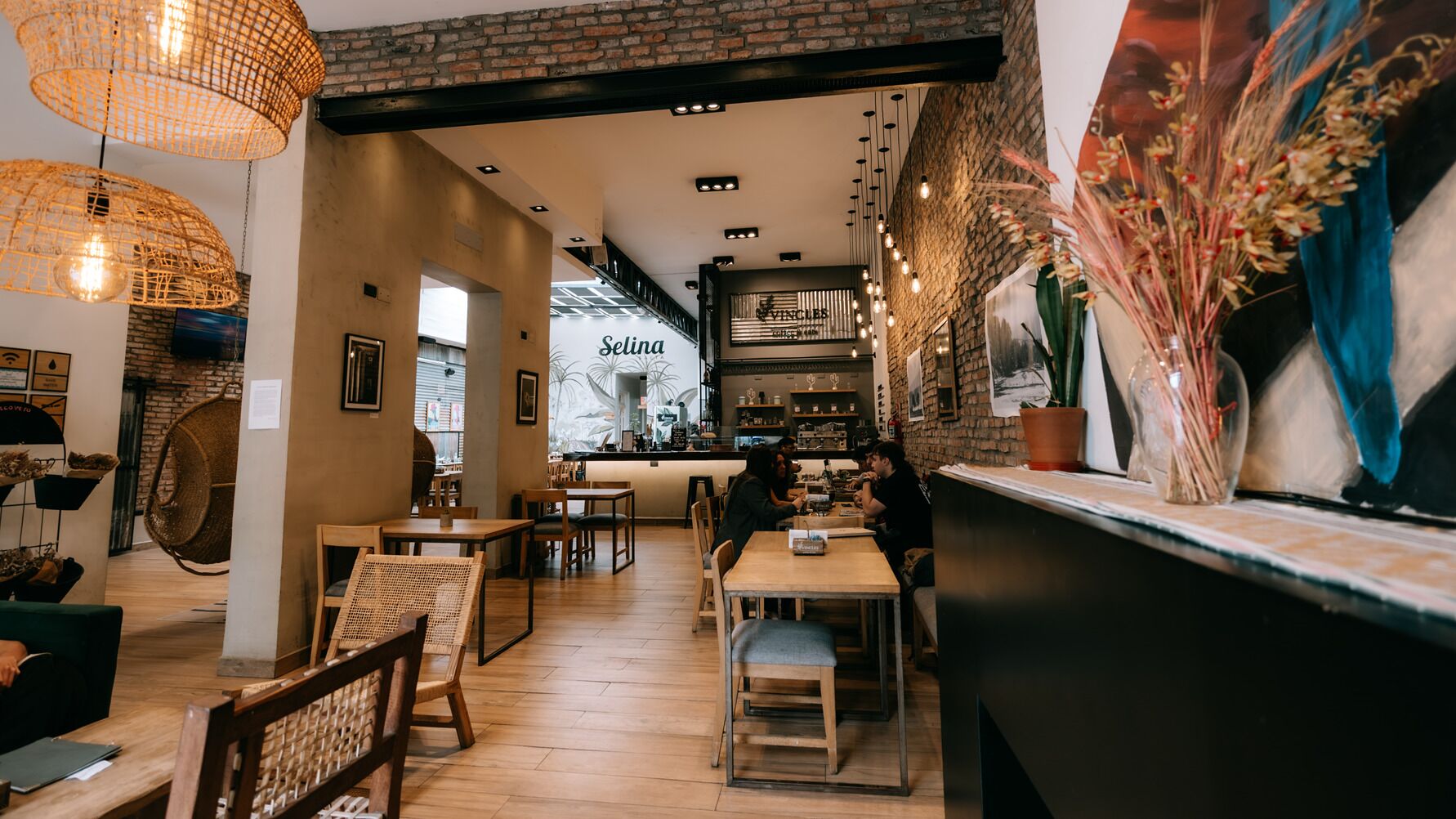 A café interior with wooden tables and chairs, a bar area, and a visible menu board.
