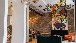 Un área de descanso moderna con una pared de ladrillo, un sofá verde y un mural de aves coloridas.