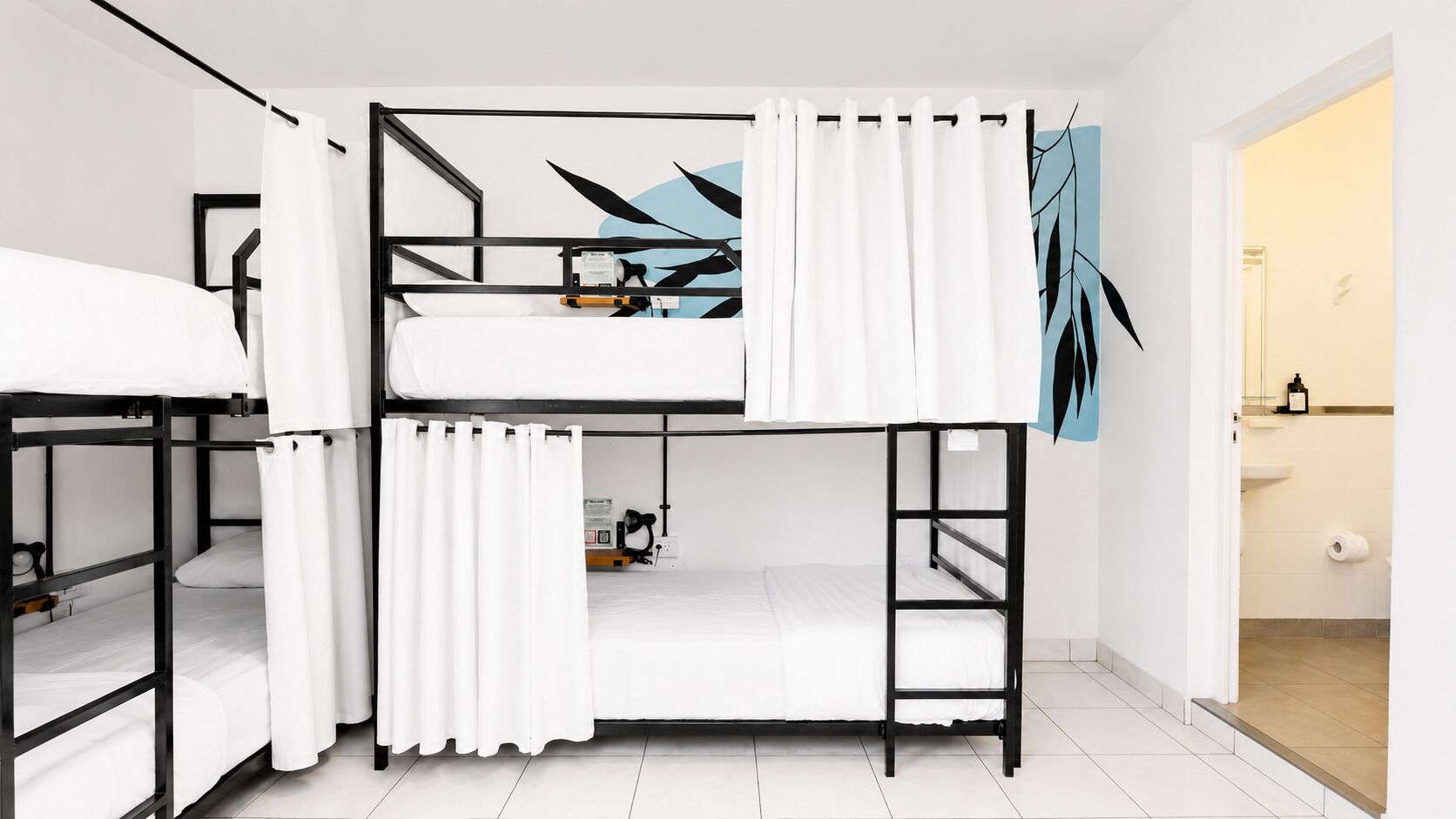 Habitación con literas, una cortina blanca, un escritorio pequeño y una obra de arte en la pared.