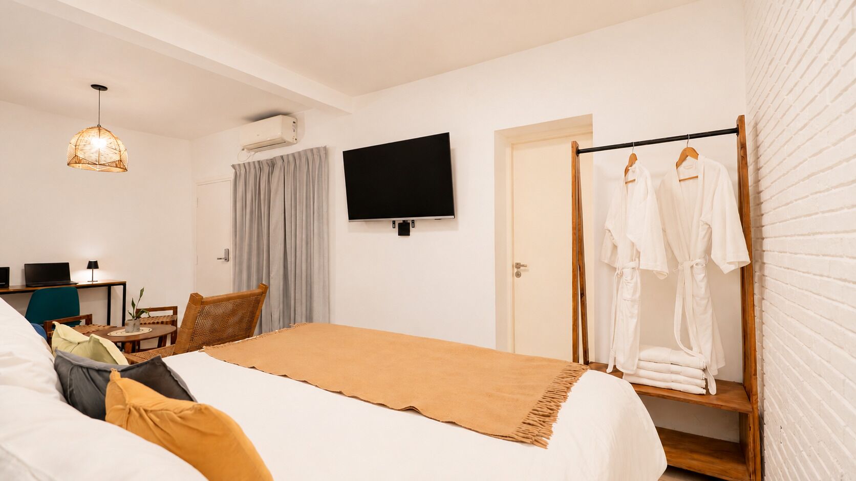 Hotelkamer met een bed, een televisie, een bureau met een laptop, een stoel en een kledingrek.