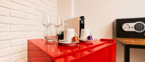 Ein rotes Tablett mit einer Kaffeemaschine, Tassen und einem Glas auf einem Tisch.