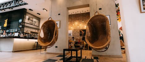 Um interior moderno com cadeiras de vime suspensas, um espaço de bar e uma parede de tijolos.