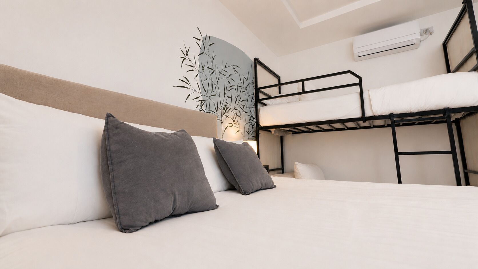 A bunk bed room with a headboard, pillows, and an air conditioning unit.