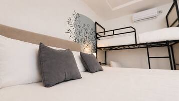 Quarto com beliche, cabeceira, almofadas e ar condicionado.