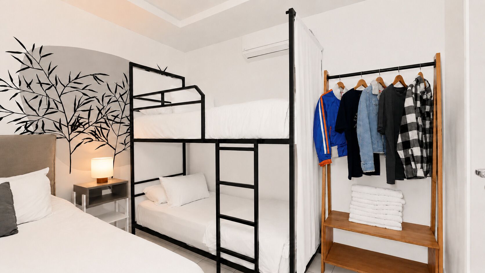 A bunk bed with a bedside table, a wall-mounted lamp, and a clothing rack with folded clothes.