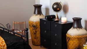 A bedroom with a bed, a dresser, two large vases, a globe, and a lit candle. - Remodeled historical loft walking distance from the Square. (Holly Springs)
