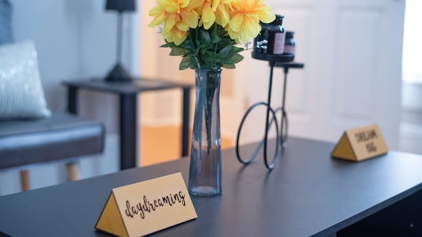 A table with a vase of yellow flowers, a name card, and a sign reading "Dreaming." - Remodeled historical loft walking distance from the Square. (Holly Springs)