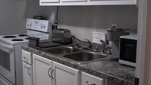 A kitchen with white cabinets, a granite countertop, a stove, a toaster, and a coffee maker. - Remodeled historical loft walking distance from the Square. (Holly Springs)