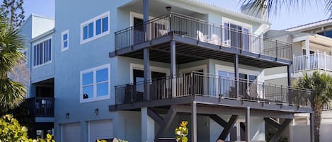 Un edificio residencial de varios pisos con balcones, garaje y un patio con mobiliario exterior.