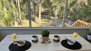 Une table en bois sur laquelle se trouvent deux bols de fruits, deux verres de jus d’orange et une petite plante en pot.