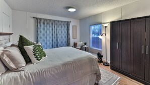 Une chambre avec un grand lit, une armoire en bois foncé et une fenêtre avec des stores.