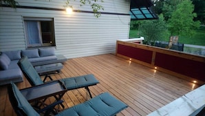A covered deck with a seating area, including a sofa and chairs, and a small table.