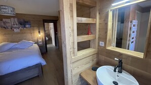 Een houten kamer met een bed, een witte wastafel en een spiegel.